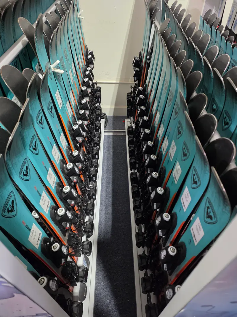 Teal Rossignol skis with Look Kid-X bindings arranged on racks